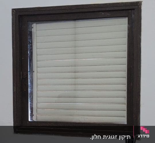 חלון עם תריסים סגורים במסגרת מתכת